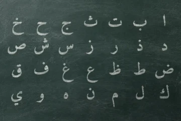 Slate with the 28 letters of the Arabic alphabet chalked in hija’i order, four rows of seven, set in Amiri